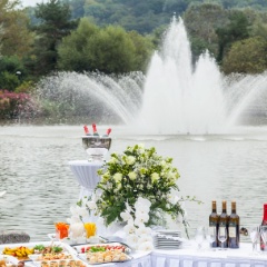 Hochzeitsapéro aufgebaut auf Tischen vor einem Springbrunnen auf Wasser