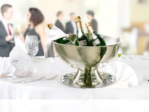 Champagnerflaschenen in einem silbernen Champagnerkühler auf einem runden, gedeckten Tisch