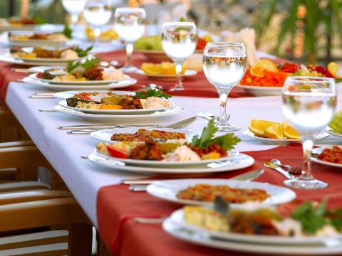 Mehrere Teller mit Essen und mit Wasser gefüllte Weingläser auf einem gedeckten Tisch